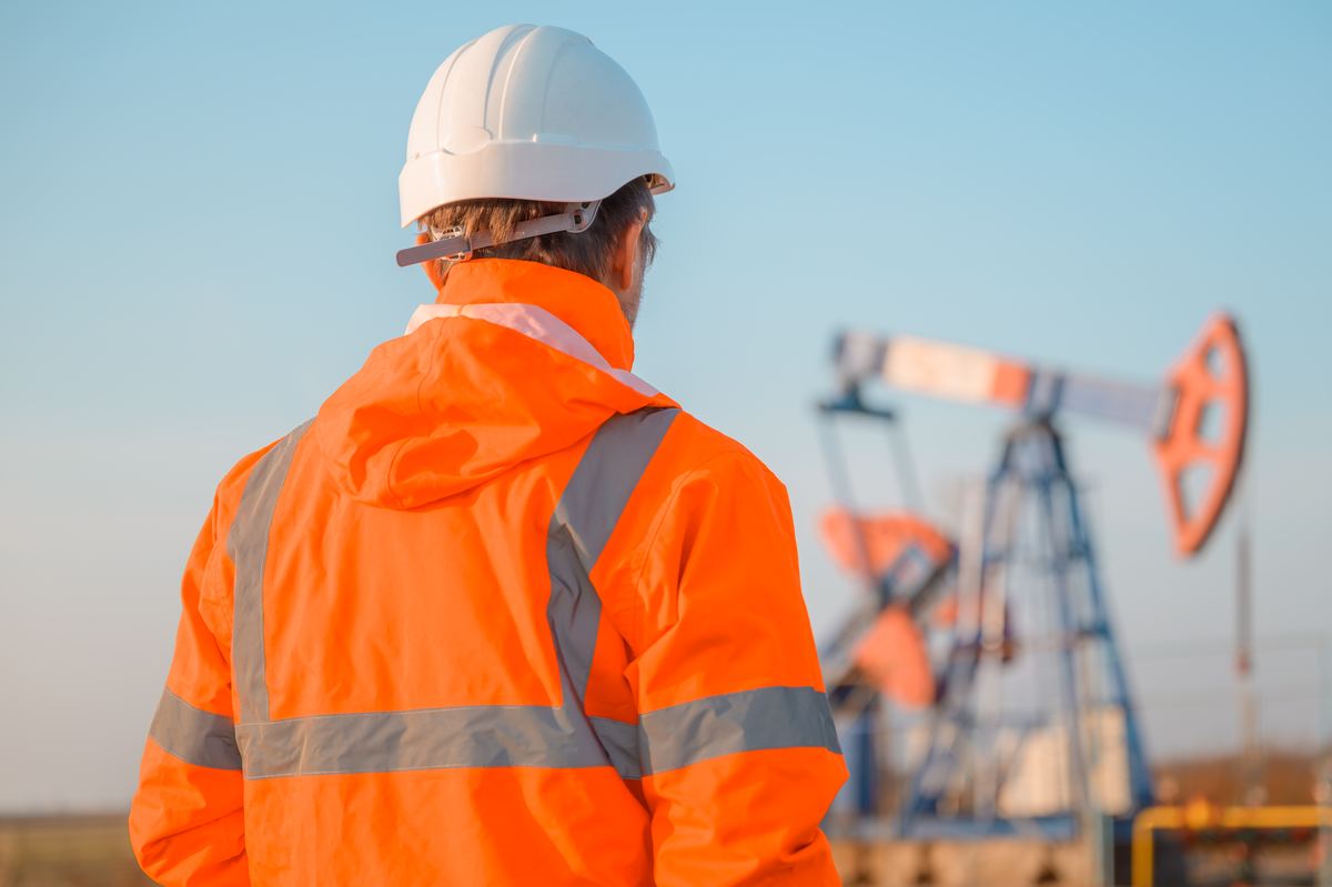 Oil and gas engineer inspecting a pump jack at a well site