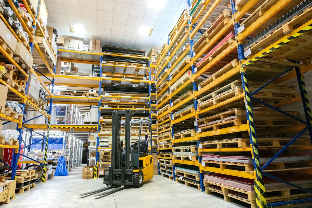 Forklift operating between warehouse racking aisles